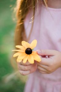 une enfant joue avec une fleur