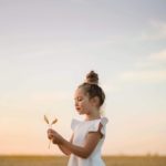 une enfant joue avec une fleur