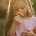 une enfant joue avec une fleur